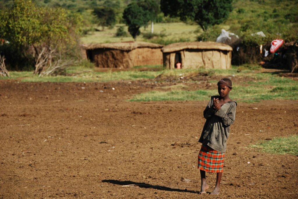 A young girl stands barefoot on the ground in Nakuru County, Kenya, showcasing cultural innocence.